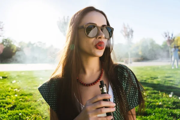 Felice moda sorridente Donna in occhiali da sole fumo vaporizzatore sulla strada, fumo — Foto Stock