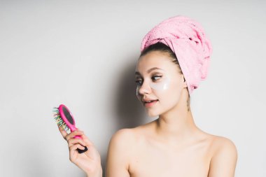 Kafasındaki bir tarak onun elinde bakarak gülümseyen bir havlu ile kız