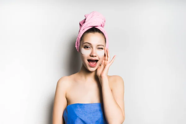 Mädchen mit einem Handtuch auf dem Kopf lächelt zwinkert und spürt ihr Gesicht — Stockfoto
