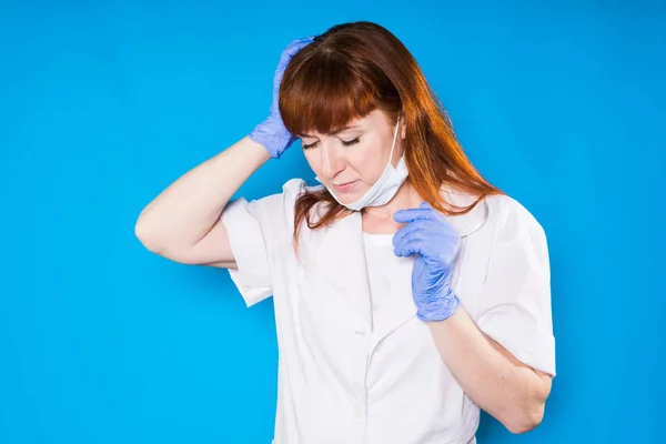 A frustrated woman doctor upset her head on a blue background