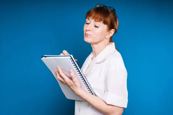 Ärztin in Brille macht sich nachdenklich Notizen in einem Blatt Papier — Stockfoto