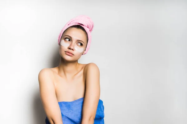 Menina com uma toalha na cabeça olha pensativamente de lado — Fotografia de Stock