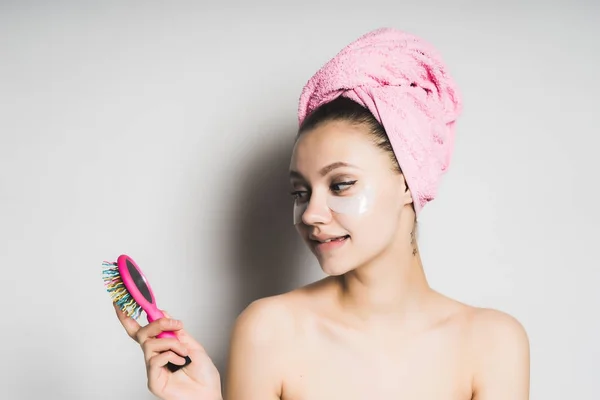 Ragazza con un asciugamano sulla testa sorridente guardando un pettine nelle sue mani — Foto Stock