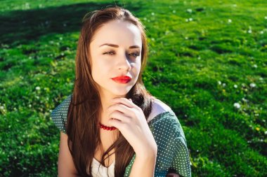 Şüpheci kadınla çimenlerin üzerinde oturan bir kırmızı dudaklar