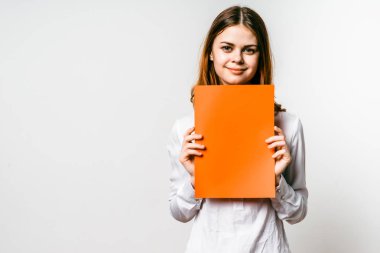 turuncu bir dosya tutarak gülümseyen kız öğrenci