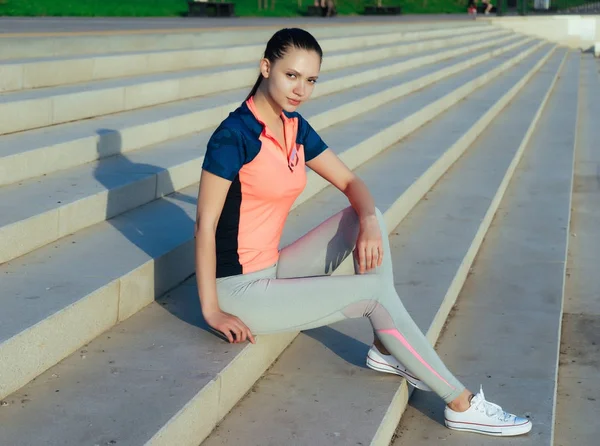 girl in sports uniform posing sitting on stairs