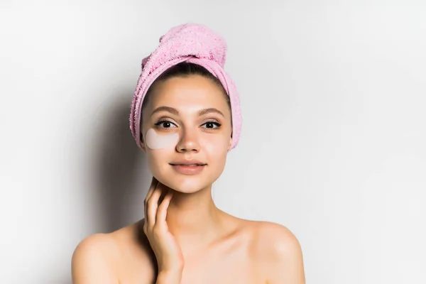 Menina com uma toalha na cabeça sorrindo sentindo seu rosto — Fotografia de Stock