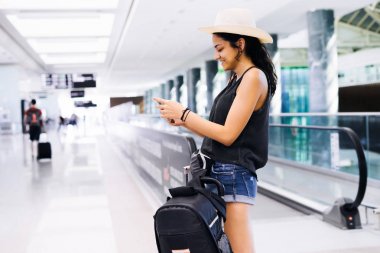 Havaalanında Smartphone kullanan kadın seyahat. Cep telefonu uygulaması terminal ya da tren istasyonu ile yatılı zaman kontrol genç Doğu yolcusu. Turizm tatil.