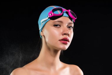 Siyah bir zemin üzerine bir genç kadın yüzücü güvenle kameraya benziyor. Motivasyon ve başarı