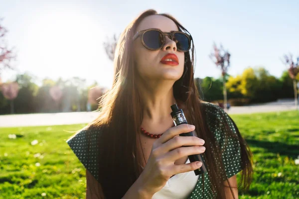 Felice moda sorridente Donna in occhiali da sole fumo vaporizzatore sulla strada, fumo — Foto Stock