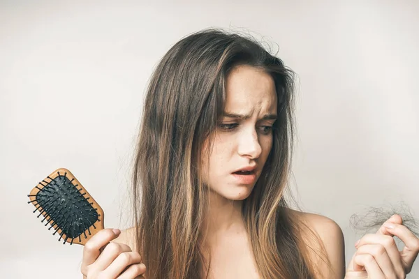 Девушка с расческой в руках с ошеломленным выражением расстроена из-за порванного лома волос — стоковое фото