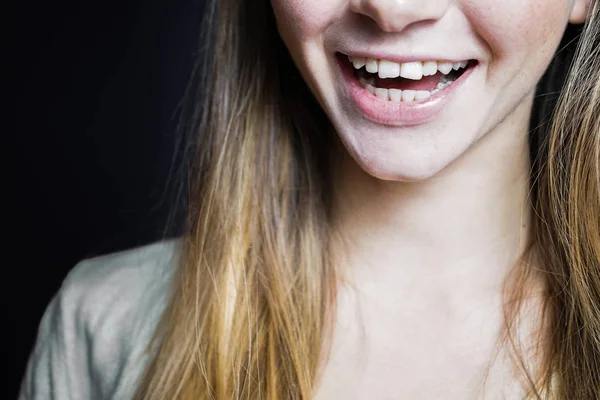 Sorridente ragazza ridente mostrando i denti su uno sfondo nero — Foto Stock