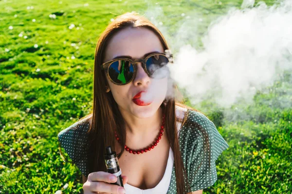 Feliz moda sonriente Mujer en gafas de sol fumar vapor en la calle, humo — Foto de Stock