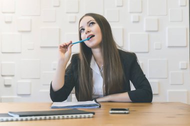 düşünceli sevimli kız ofiste oturan ve elinde kalem tutan takım