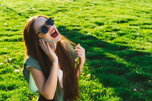 Удивлённая женщина разговаривает с мобильником, девушка в солнечных очках — стоковое фото