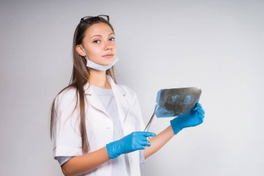 güzel kız beyaz paltolu bir x-ışını tutar ve kameraya benziyor