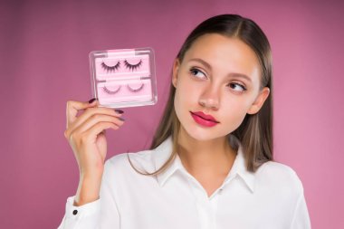 Ellerini, izole pembe bir arka plan üzerinde sahte kirpik şirin güzel kız güzel dudaklı tutar