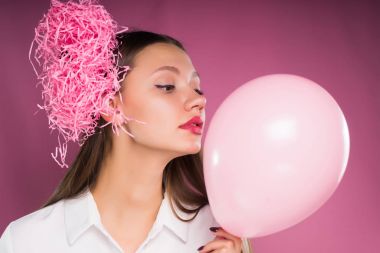 büyük gözlü bir kız pembe topu tutuyor ve öfkeyle uzağa görünüyor