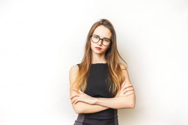 Serious business young woman in big glasses and a beautiful black dress looks directly into the camera