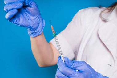 mavi bir arka plan üzerinde bir eldiven, bir şırınga yakın çekim, holding hemşire izole