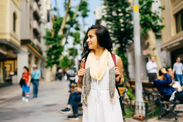 Красива дівчина моди в білій сукні з рюкзаком на вулиці подорожує — стокове фото
