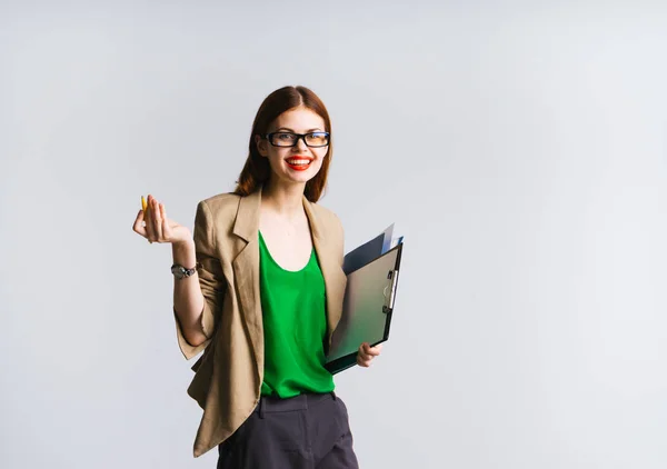 Ein lustiges rothaariges Mädchen in grünem Pullover und Brille lacht und hält einen Ordner mit Papieren in der Hand — Stockfoto