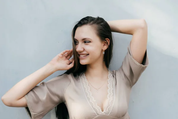 Bella ragazza carina in tenero vestito beige sorridente e guardando altrove — Foto Stock