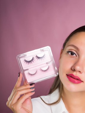 büyük dudakları ve gözleri sahte kirpik elinde tutan güzel şirin kız