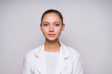 küçük bir gülümseme onun beyaz ceket ciddi bir kızla düz duran ve doğruca kameraya bakıyor