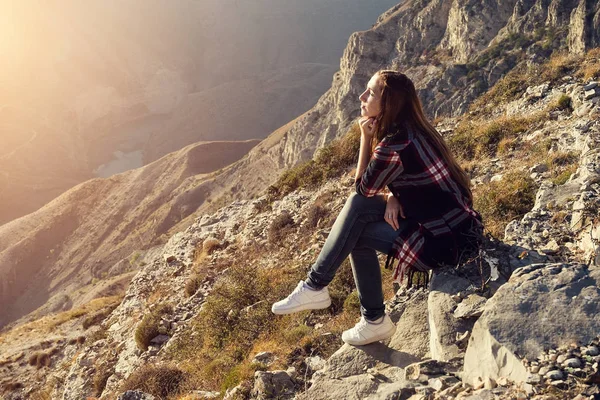 Девушка в клетчатой рубашке сидит в горах на закате, прекрасный вид — стоковое фото