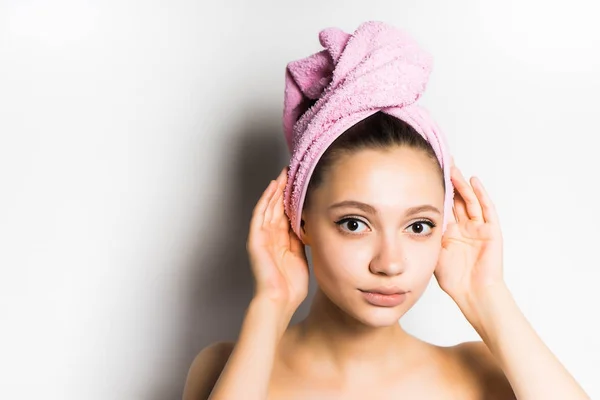 Menina após o chuveiro com uma toalha rosa na cabeça olhando para a câmera, isolado — Fotografia de Stock