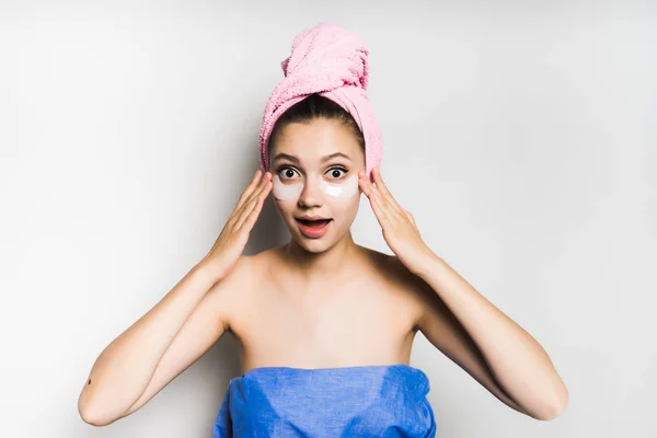 Menina com toalha na cabeça depois de chuveiro coloca no rosto sob os olhos remendos — Fotografia de Stock