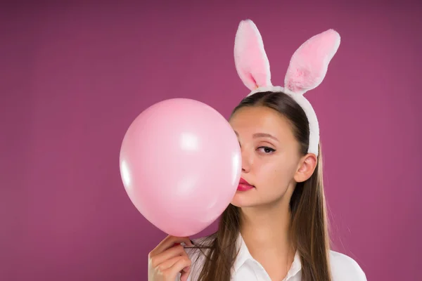 Mooi meisje met roze oren op haar hoofd houdt een bal in haar handen, geïsoleerd — Stockfoto
