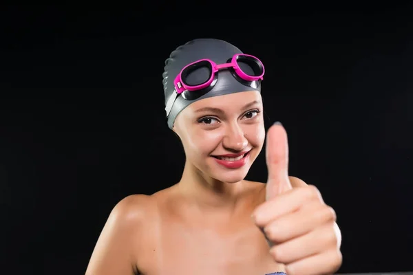 Смеющаяся девушка идет к бассейну и показывает большие пальцы вверх, изолированные на черном фоне — стоковое фото