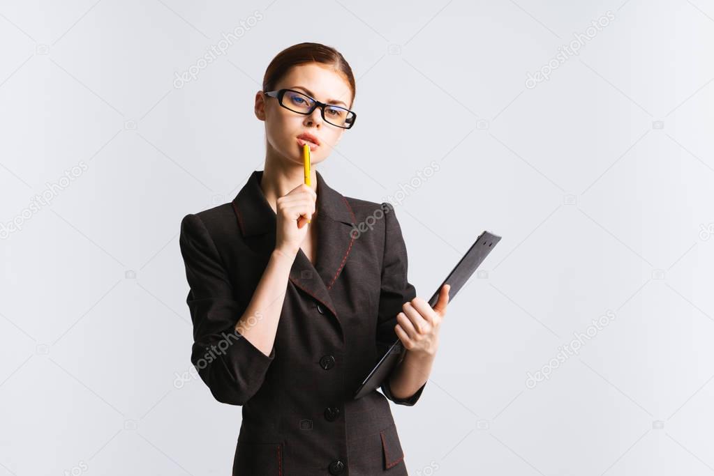 attentive red-haired girl with glasses holds documents and pencil in hands, looks away