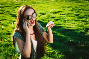 Mutlu kadın çim üzerinde bir şey gösteren gözlük kullanan mobil