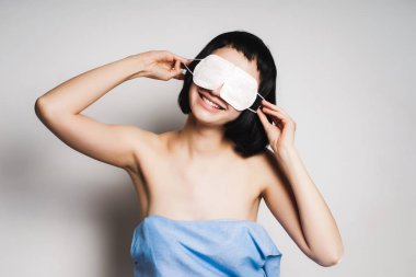 havlu uyumak için bir maske gözleriyle kapsayan gülümseyen kız
