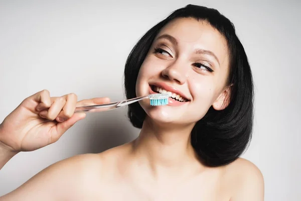 Menina com sorrisos de cabelo preto, segura uma escova de dentes em suas mãos — Fotografia de Stock