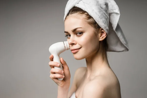Menina com uma toalha na cabeça limpa o rosto em um fundo branco — Fotografia de Stock