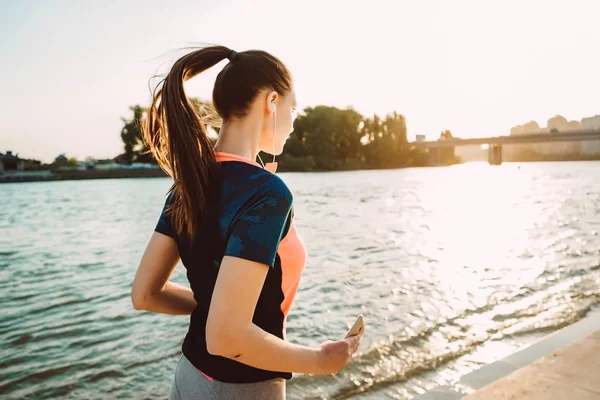 Дівчина в спортивній формі виконує вечірню пробіжку вздовж річки — стокове фото