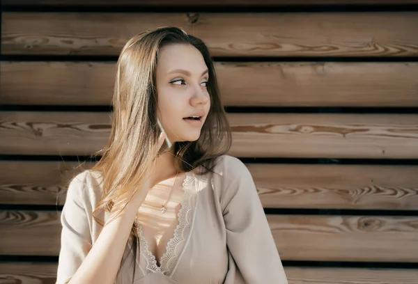 Girl holding her hair against the background of a wooden wall — Stock Photo, Image