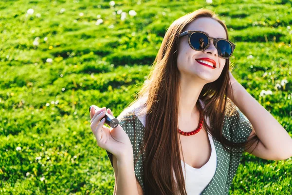 Happy fashion smiling Woman in sunglasses smoking vape on street,smoke — Stock Photo, Image