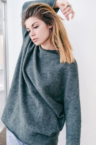 Cute girl with huge gray sweater looks down — Stock Photo, Image