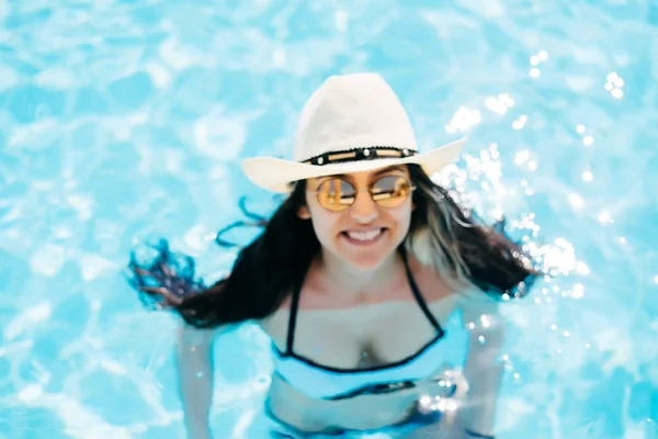 Blurred background with woman face in pool, girl in sunglasses