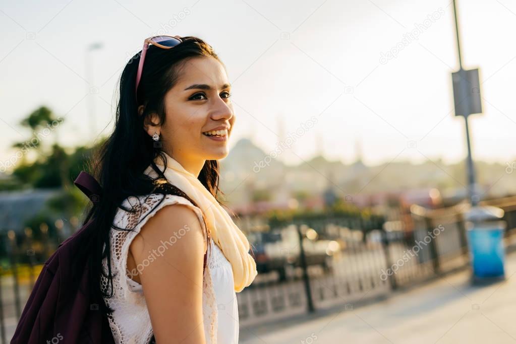 Girl traveler with a backpack walking around the city at sunset
