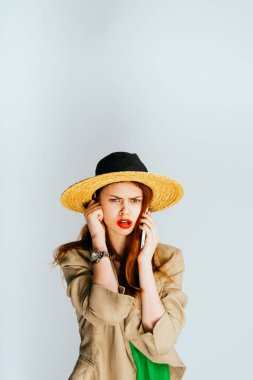 Hasır Şapkalı bir kız telefonda konuşuyor ve kızgın görünüyor