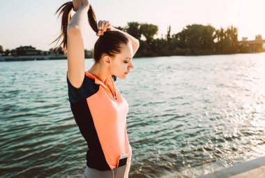 Sportif üniformalı bir kız onu helezon ayarlama nehir arka planı standları