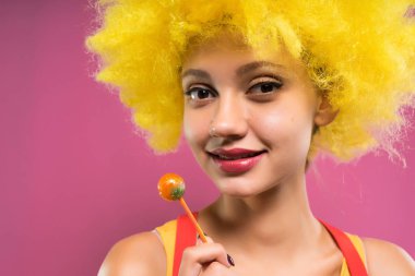 Palyaço kıyafetli bir şeker tutan gülümseyen kız