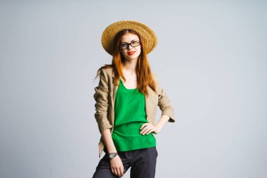 Kızıl saçlı kız bir şapka ve ayakta ve gülümseyen bir yeşil yelek