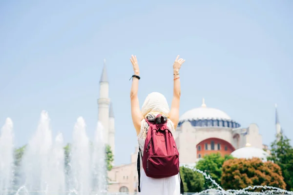 Невпізнавана жінка в шарфі з рюкзаком на тлі мечеті та фонтану. Літня відпустка, мандрівник — стокове фото
